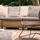 Patterned pouf and rattan chair on cozy wooden patio or deck with cushions and pillows on sofa and lanterns