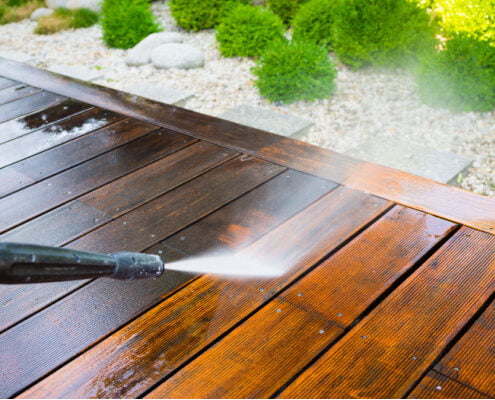 Cleaning deck with a power washer after winter - high water pressure cleaner on wooden deck surface