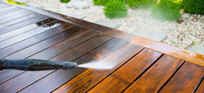 Cleaning deck with a power washer after winter - high water pressure cleaner on wooden deck surface